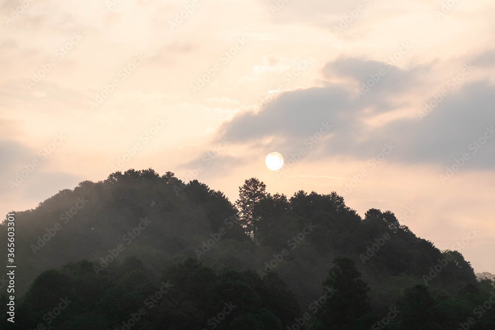 朝靄の山から昇る太陽