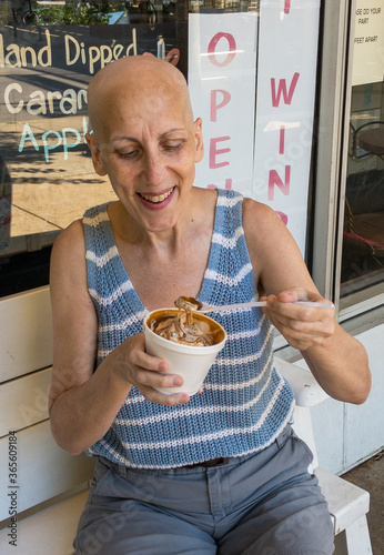 bald woman smiling while eating ice cream