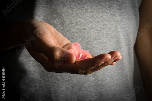 Fototapeta Naklejka Na Ścianę i Meble -  Female holding pink condom in hand.