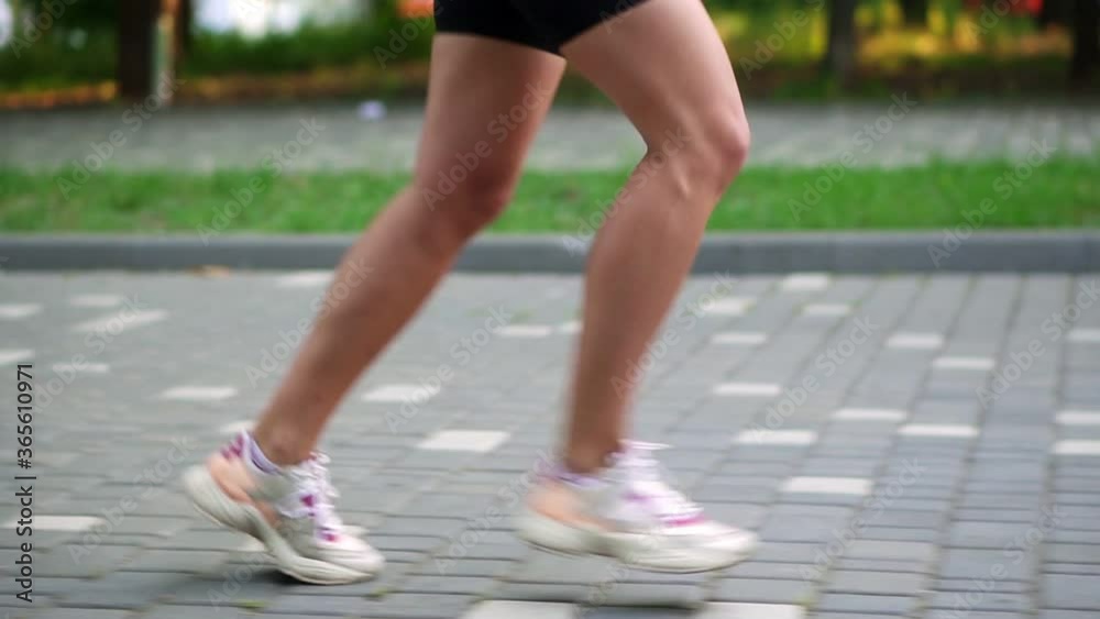 Female athlete's feet running at the park. Fitness woman jogging outdoors. Exercising on park pavement. Healthy, fitness, wellness lifestyle. Sport, cardio, workout concept. Side view. Slow motion Female athlete's feet running at the park. Fitness woman jogging outdoors. Exercising on park pavement. Healthy, fitness, wellness lifestyle. Sport, cardio, workout concept. Side view. Slow motion