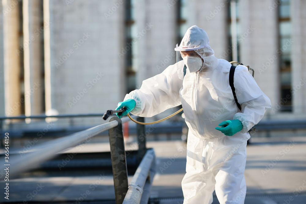 Male cleaner in protective suit disinfecting public area in the city due to coronavirus epidemic. Male cleaner in protective suit disinfecting public area in the city due to coronavirus epidemic.