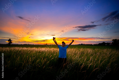 A man  show camera in  a field of flowers  grass and evening light.
