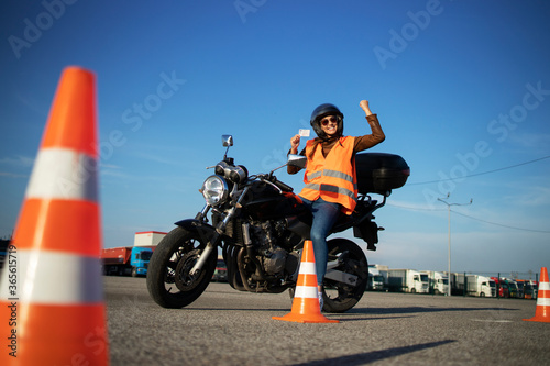 Motorcycle driving school. Student showing motorcycle driving license as successfully finished riding lessons. photo