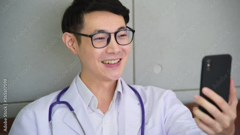 Professional Asian psychologist doctor in work coat uniform and stethoscope using smartphone and video call facetime talking to people with smile and happy mood at workplace office Professional Asian psychologist doctor in work coat uniform and stethoscope using smartphone and video call facetime talking to people with smile and happy mood at workplace office