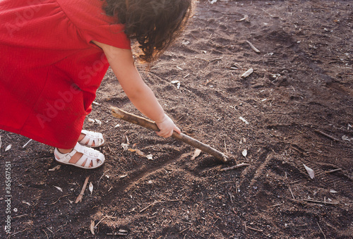 little girl plays with dirt in the park away from adults