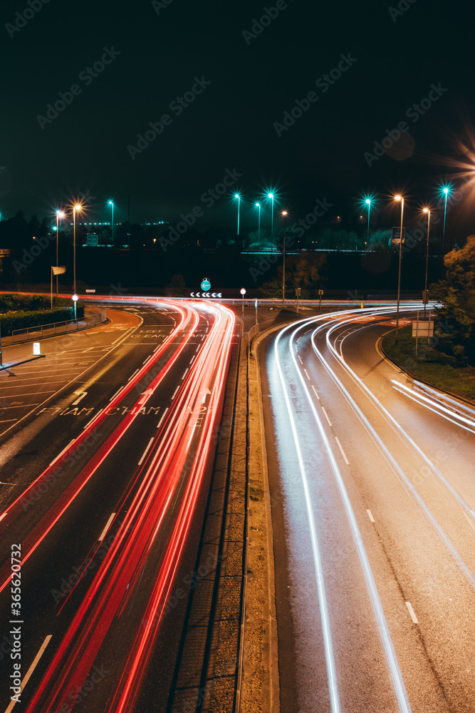 light trails of cars at night approaching a roundabout