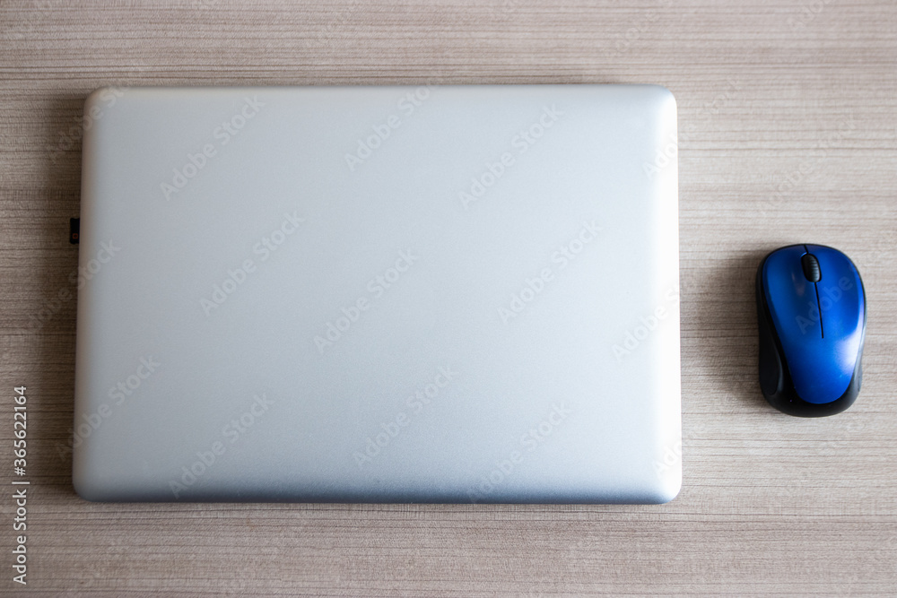 A laptop with wireless mouse on a wooden table. A laptop with wireless mouse on a wooden table.