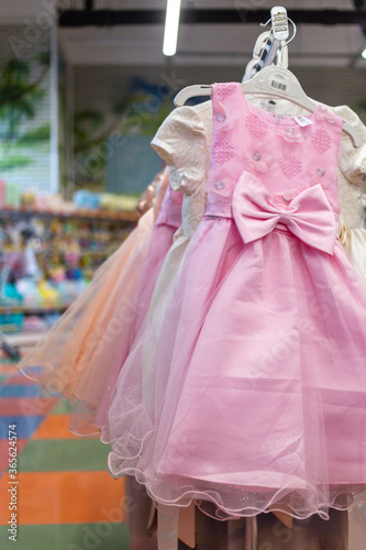 pink children s dress with an anticom on the belt hanging on a hanger in the store. High quality photo