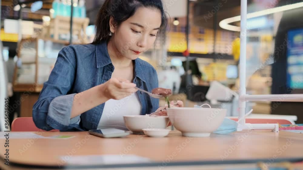 Asian woman sitting separated in restaurant eating food .keep social distance for protect infection from coronavirus covid-19, restaurant and social distancing concept.4k footage. Asian woman sitting separated in restaurant eating food .keep social distance for protect infection from coronavirus covid-19, restaurant and social distancing concept.4k footage.