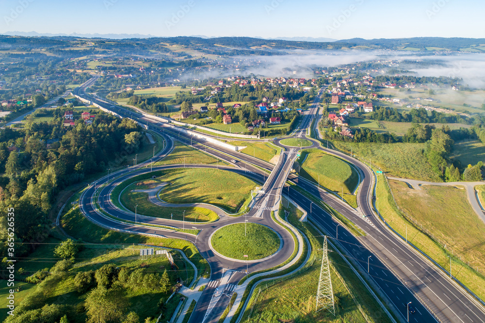 New highway junction in Poland on national road no 7, E77, called Zakopianka. Overpass crossroad with traffic circles, slip roads and viaducts near Rabka. Aerial view. Far view of Tatra Mountains