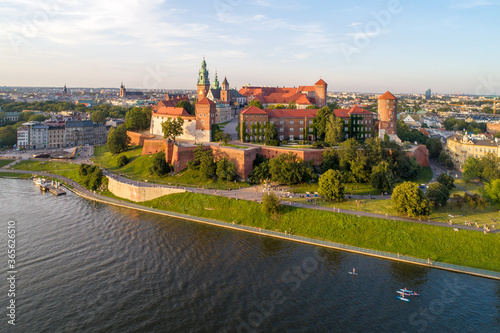 Royal Wawel Cathedral and castle in Krakow, Poland. Aerial view in sunset light. Vistula River with people on stand up puddles, riverbank with park. promenade and  walking people