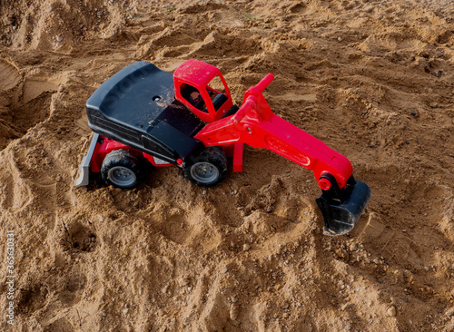 Red plastic excavator on the sand.