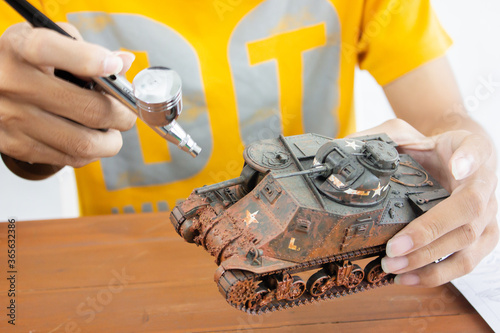 man painting scale model WW2 tank on table. Hobbie. photo