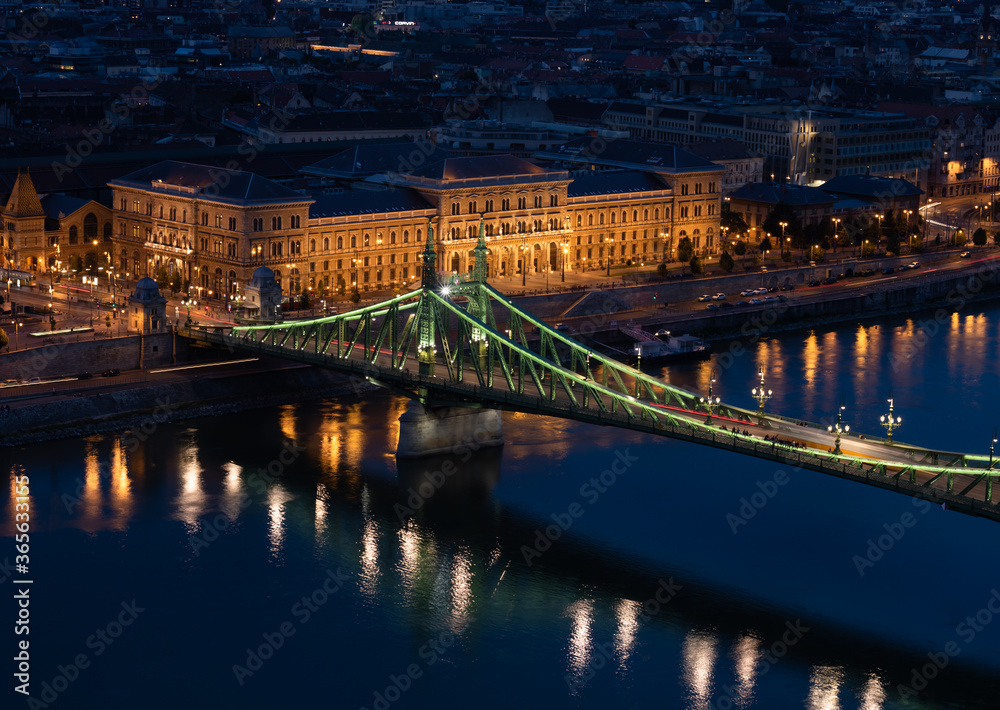 Beautiful midnight scene in the lovely Budapest with the green Petőfi Bridge, trams and Corvinus University building