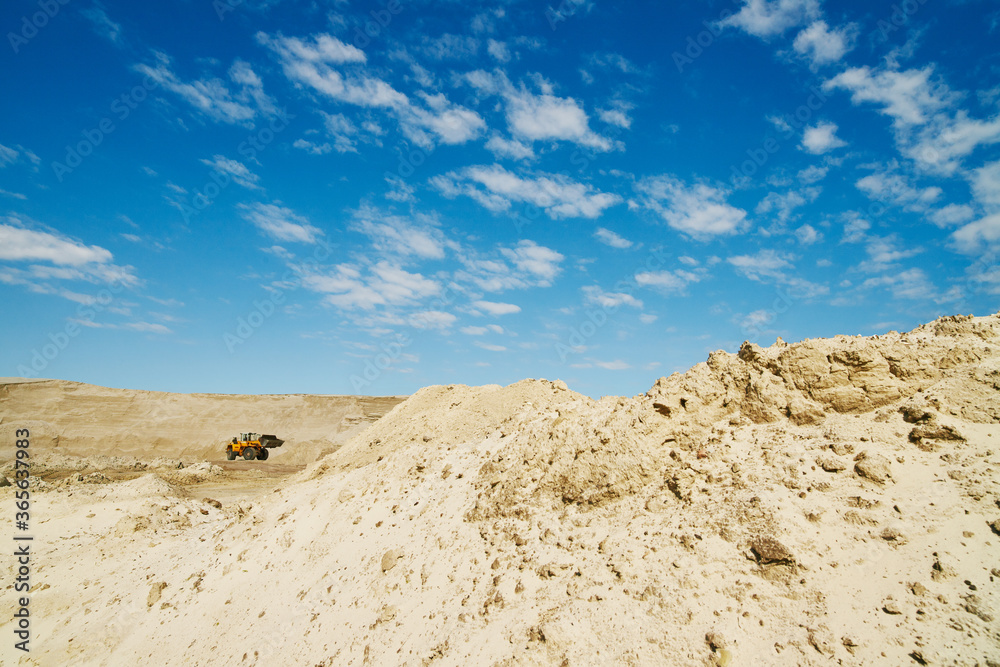 Panoramic view of a bulldozer in a sand quarry on a clear spring day.