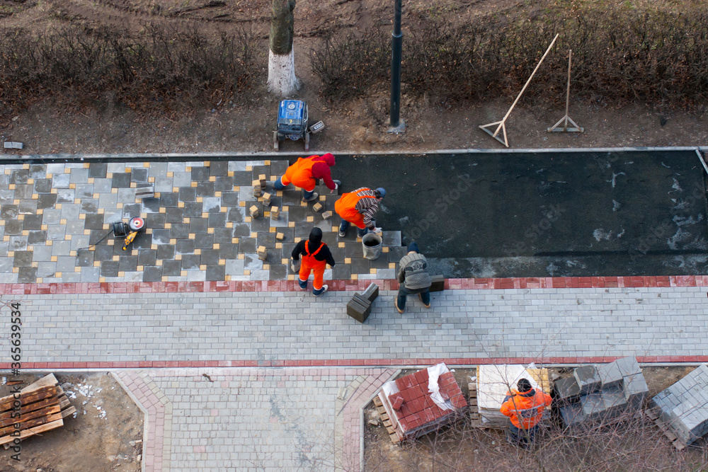 The masters lays paving stones. Sidewalk Repair. Road Workers Aerial View.