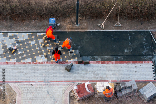 The masters lays paving stones. Sidewalk Repair. Road Workers Aerial View.