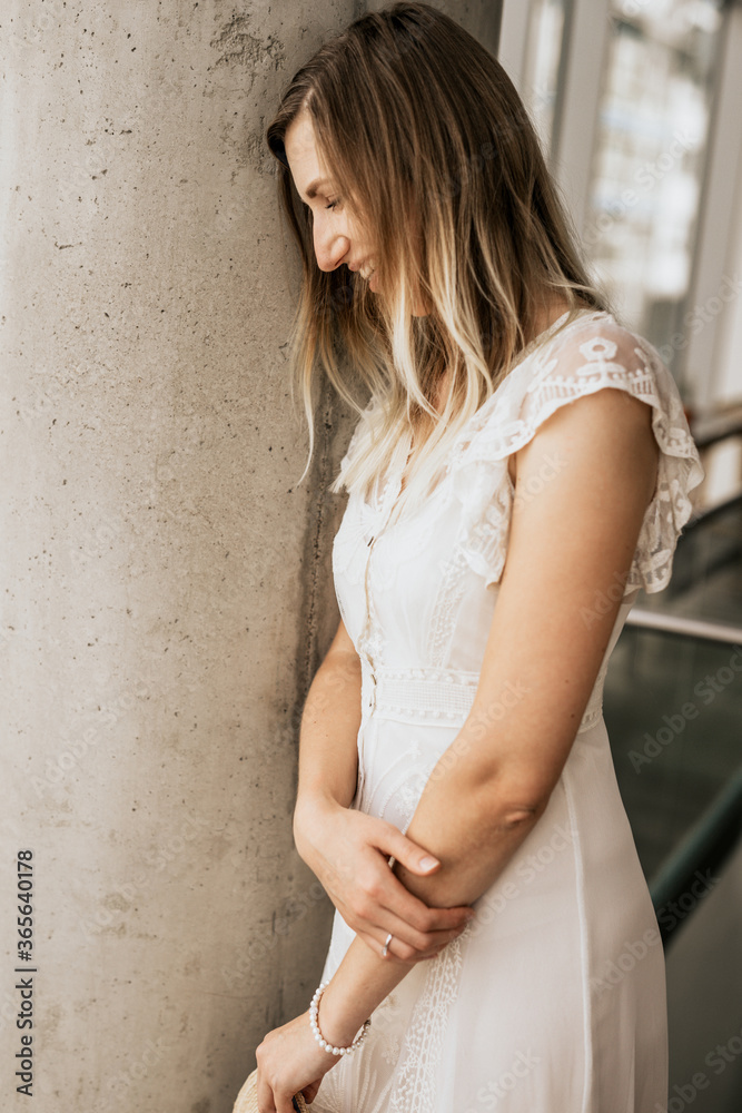 Fototapeta premium Smiling attractive woman wearing white dress indoor