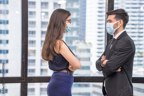 Business woman stands with her arms crossed and confident, facing with a businesswoman, wearing a mask to prevent Corona infection at office.New Normal concept.