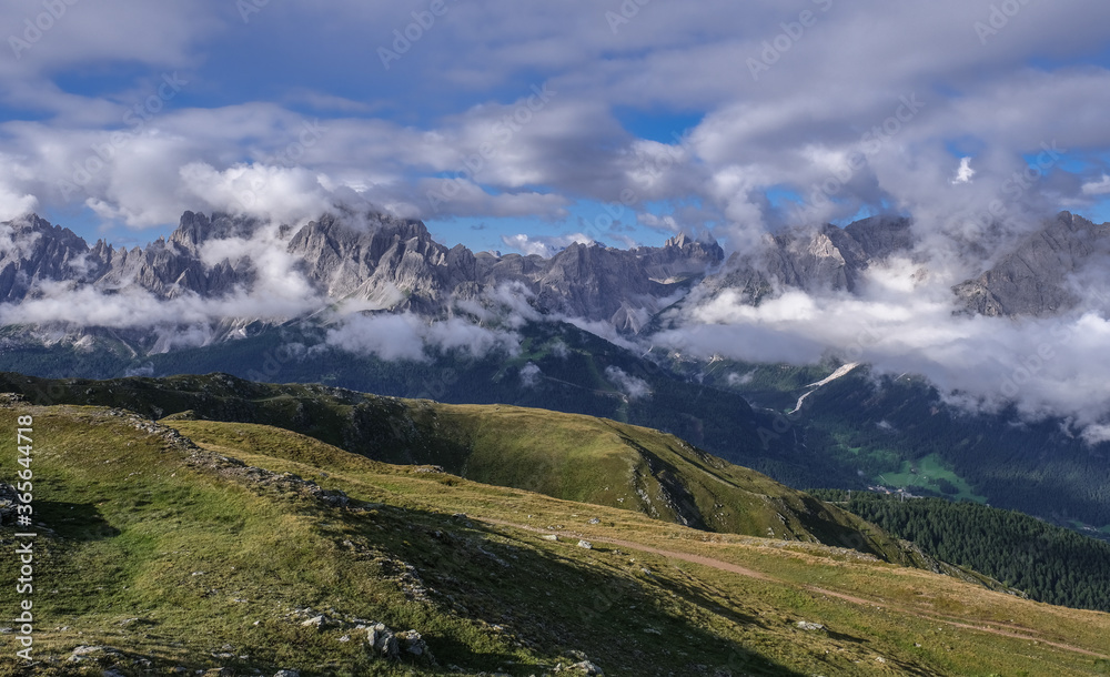 Obraz premium Scattered clouds above and below the Sesto Dolomites massif in Italy as seen from the Carnic Peace Trail along the Carnic Alps on the way up the Hornisch Eck summit, Carnic Highroute trek, Austria.