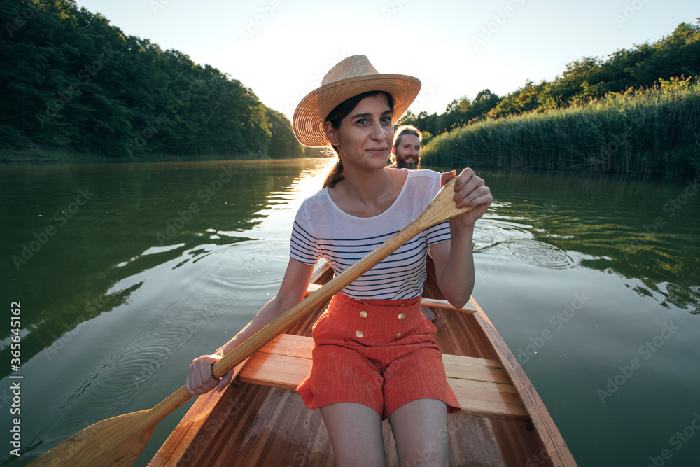 Young woman paddling canoe with her partner Young woman paddling canoe with her partner