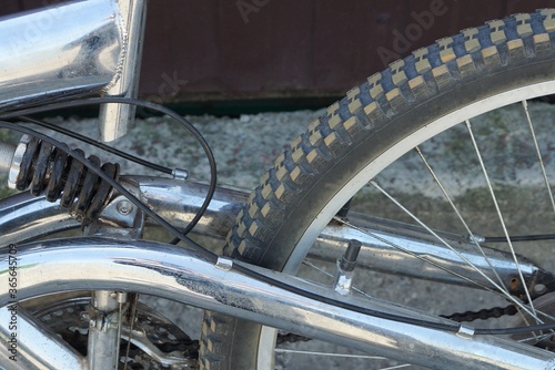 part of a sports bike with a white metal frame and a black spring with a wheel and a black tire
