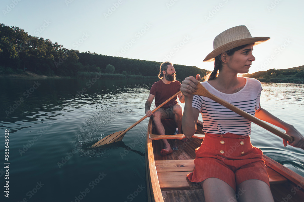 Selective focus of man and woman paddling canoe and enjoy summer sunset boat ride