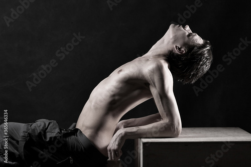 Full length of a naked young man posing against black background photo