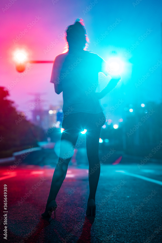 Fototapeta premium Beautiful women's back under traffic lights on the road