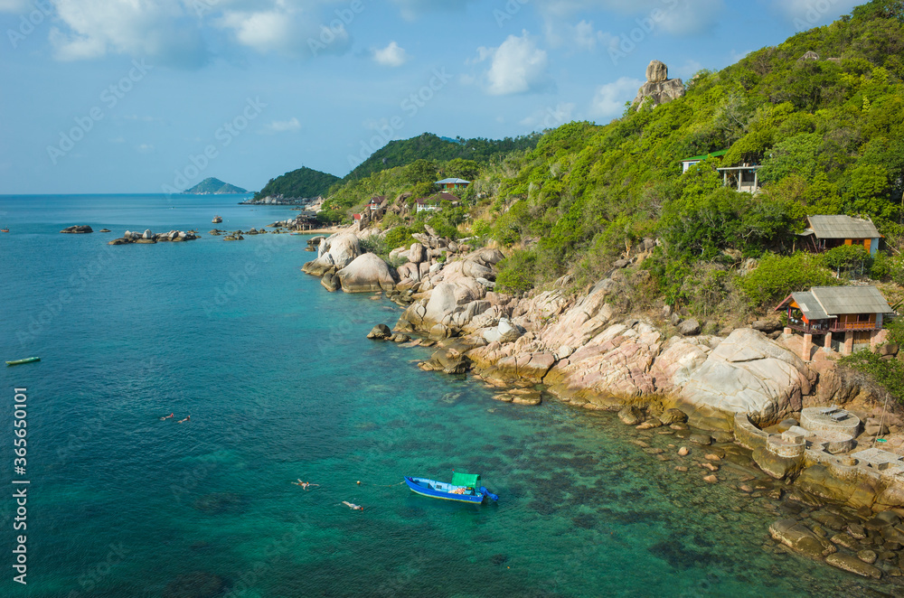Obraz premium Tropical island coastline, Coast of Koh Tao island with turquoise clear water, boat and people snorkeling, bungalows with sea view, sunny day. Famous destination for travel holidays in Thailand