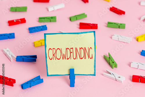 Text sign showing Crowdfunding. Business photo text project by raising a large number of small amounts of money Colored clothespin papers empty reminder pink floor background office pin photo