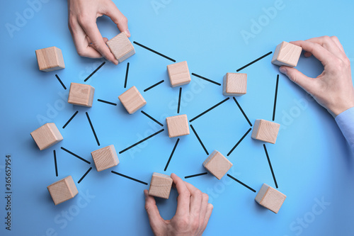 Network Community - man hands put the wooden bricks with person icon on them to blue background which are interconnected. connected people.