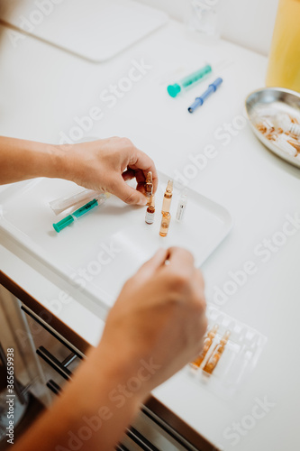  ampoules and needles on a tablet in a hospital, preparation of needles to be filled with medicine, close up of hands preparing a needle with medication