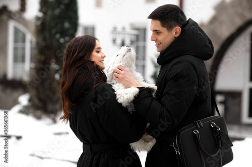 Close-up portrait oh happy young smiling couple holding hugging and stroke a dog - his new member of the family. New lovlely pet find his family. photo