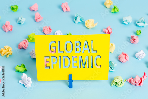 Text sign showing Global Epidemic. Business photo text a rapid spread of a communicable disease over a wide geographic area Colored crumpled papers empty reminder blue floor background clothespin photo