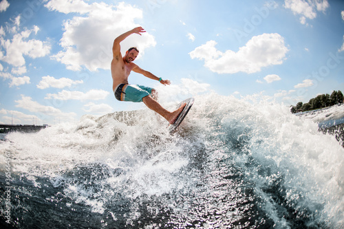 energetic male wakesurfer rides wave on board
