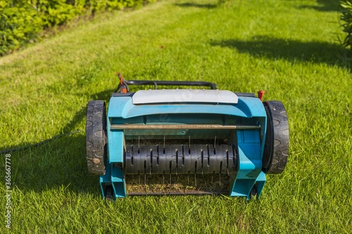 Close up view of electric lawn aerator on green grass isolated. Garden machines concept. 