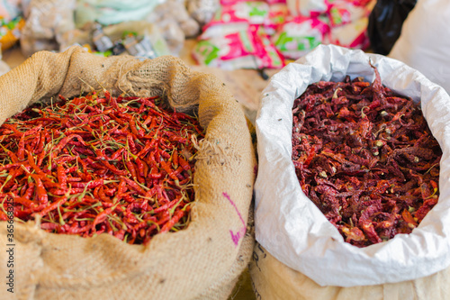 Dried red chillies and Byadagi chillies in a local market in Karnataka, India. Different variety of peppers in gunny bags for sale 
