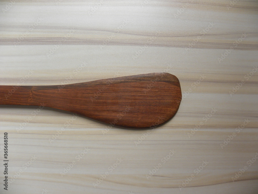 Brown color wooden curved saute Spatula kept on table