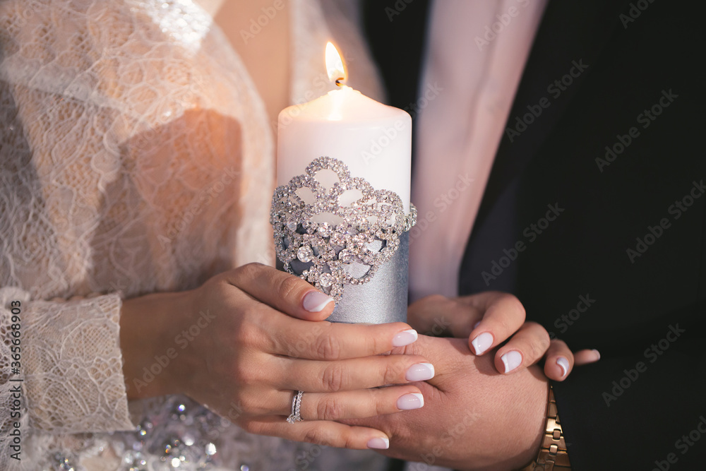 Wedding ceremony, paraphernalia, the bride and groom hold a large candle in their hand Wedding ceremony, paraphernalia, the bride and groom hold a large candle in their hand