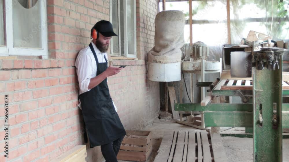 Carpenter in his own woodshop taking on the phone Carpenter in his own woodshop taking on the phone