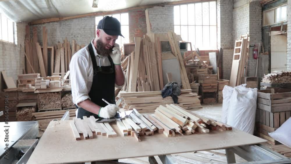 Carpenter in his own woodshop using a tablet pc and writes notes while being in his workspace. Small business concept Carpenter in his own woodshop using a tablet pc and writes notes while being in his workspace. Small business concept