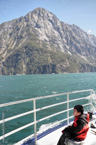 Young asian boy looking at the mountains on a ferry trip in Milford Sound, NZ