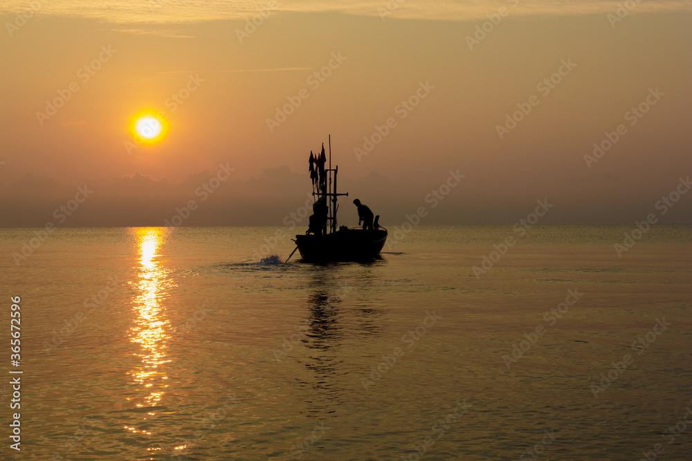 Silhouette of two people on a fishing boat that is about to go fishing in the morning sun.copy space.