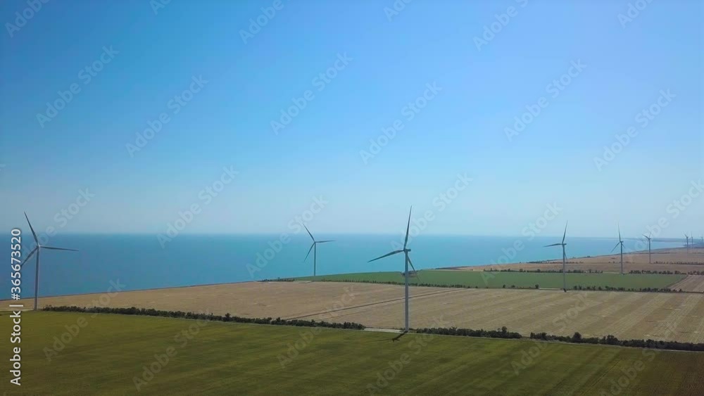 Aerial view of wind power plant by the sea. Windmills rotating by the force of the wind and generating renewable energy in a green ecological way to the planet