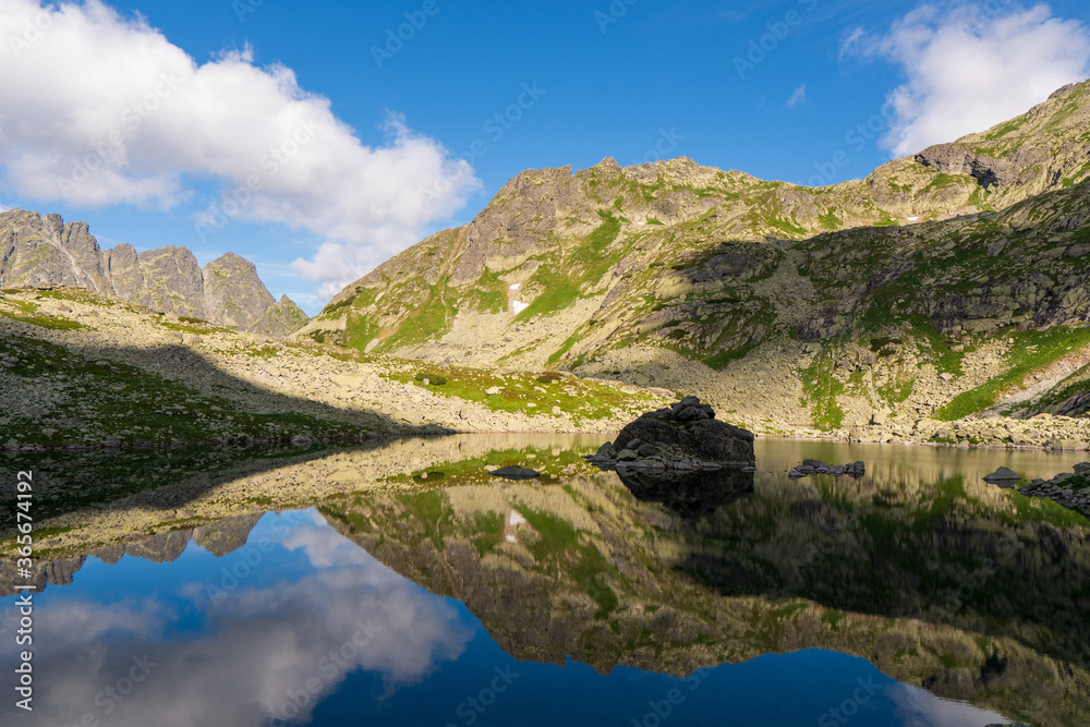 Scenic view of mountains clouds and green with a reflection in a frogs lake. Stony shore. zabie pleso. frogs lake. High Tatras, Slovakia Concept of nature and tourism