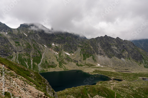 Scenic view of mountains clouds and green with a reflection in a frogs lake. Stony shore. hlincovo pleso. hlincovo lake. High Tatras, Slovakia Concept of nature and tourism