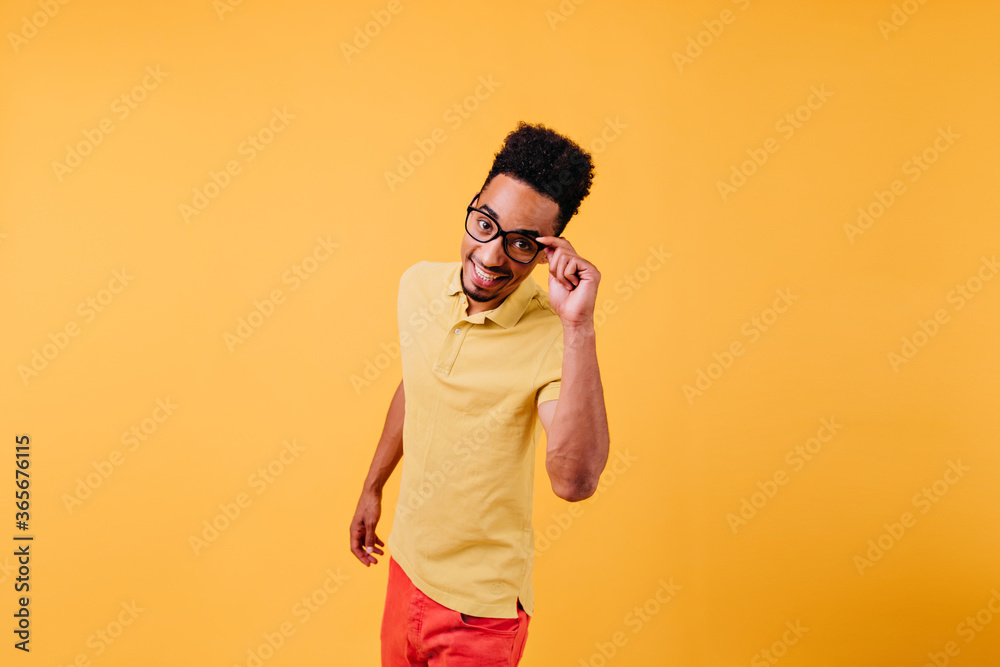 Spectacular inspired man in glasses posing in studio. Excited african guy having fun on yellow background. Spectacular inspired man in glasses posing in studio. Excited african guy having fun on yellow background.