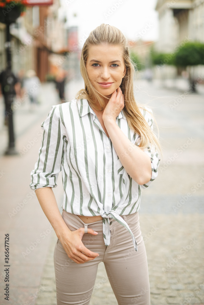 Portrait of beautiful young blonde woman in a city.