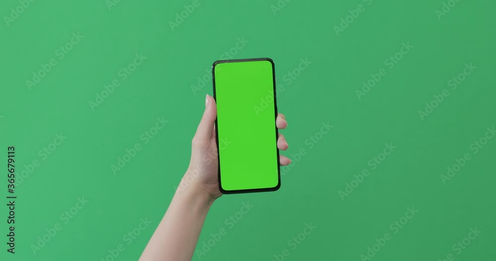 Young female hand touch smartphone with green screen on green background